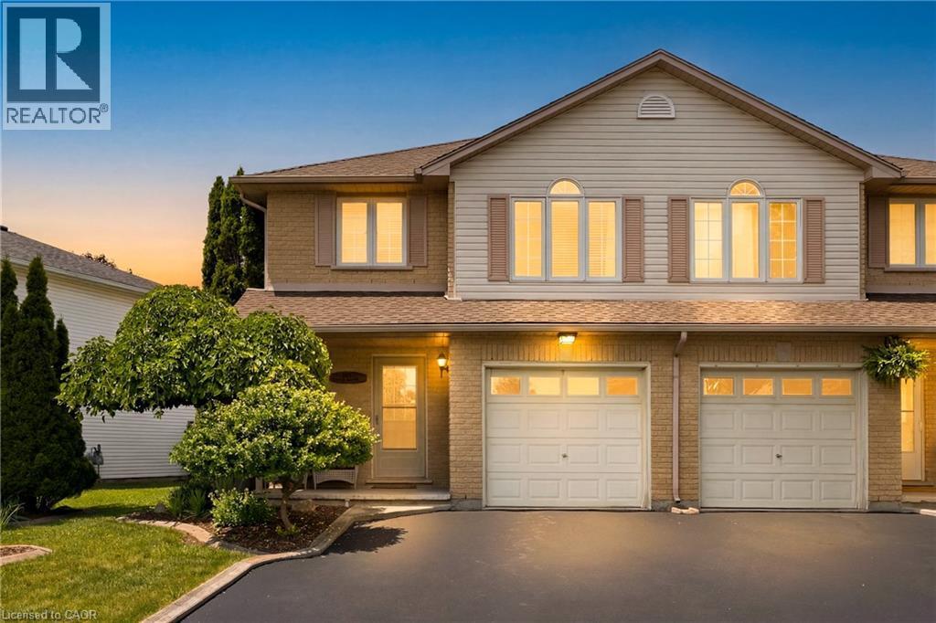 Two-story property featuring a brick and siding exterior, two garage doors with window inserts, and arched top-floor windows - 16 Scottacres Boulevard, Caledonia, ON