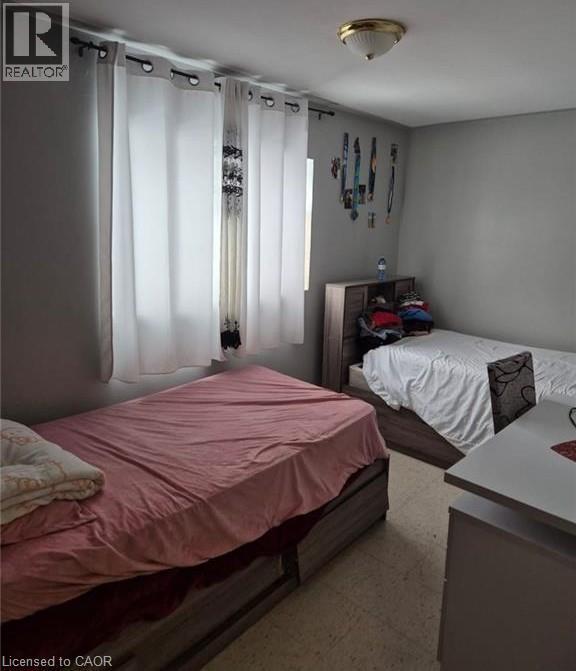 Bright bedroom featuring light gray walls and two windows with white curtains - 76 Brybeck Crescent Unit# 302, Kitchener, ON