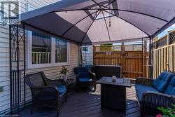 Covered outdoor deck area featuring a dark-toned privacy fence and hot tub - 