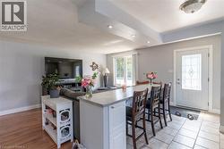 Open-concept living space featuring a breakfast bar with seating, recessed lighting, and a white entry door with decorative glass inserts - 