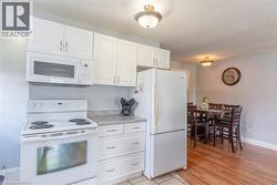 Kitchen with white cabinetry, integrated microwave, and white electric range - 