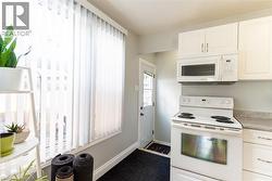Kitchen featuring white cabinetry, a built-in microwave, an electric range, and a gray countertop - 