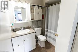 Bathroom featuring a vanity with a white basin and a surface-mount faucet, an integrated mirror with overhead lighting, and a white storage cabinet with barn door accents - 