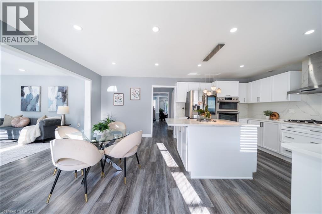 Modern kitchen featuring white cabinetry, stainless steel appliances, a center island with pendant lighting, and wood-finish flooring - 151 Baldwin Drive, Cambridge, ON