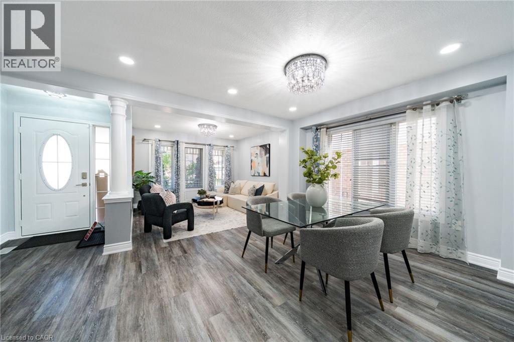 Spacious open-concept interior featuring wood-finish flooring, recessed lighting, and a crystal chandelier - 151 Baldwin Drive, Cambridge, ON