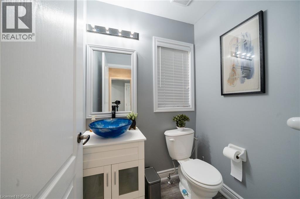 White vanity with a blue vessel sink, framed mirror, and modern light fixture - 151 Baldwin Drive, Cambridge, ON - Indoor Photo Showing Bathroom