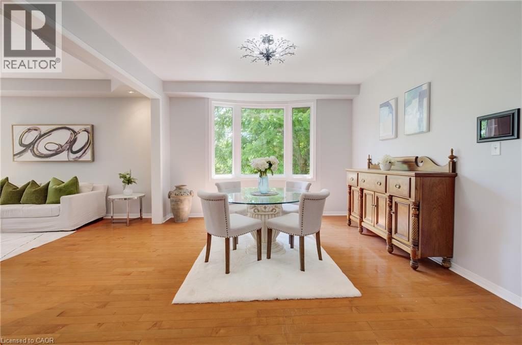 Open-concept dining area featuring wood-finish flooring, a contemporary chandelier, and a bay window - 23 Buerkle Court, Kitchener, ON - Indoor Photo Showing Dining Room