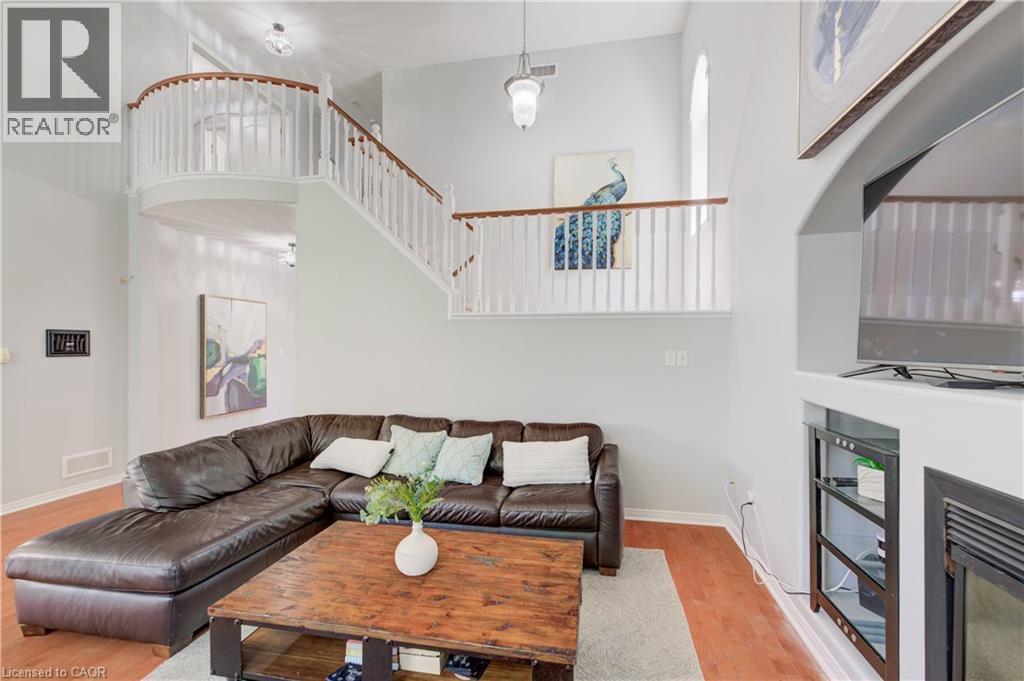 Two-story living area featuring wood-finish flooring and a built-in media niche with an electric fireplace - 23 Buerkle Court, Kitchener, ON - Indoor Photo Showing Living Room With Fireplace