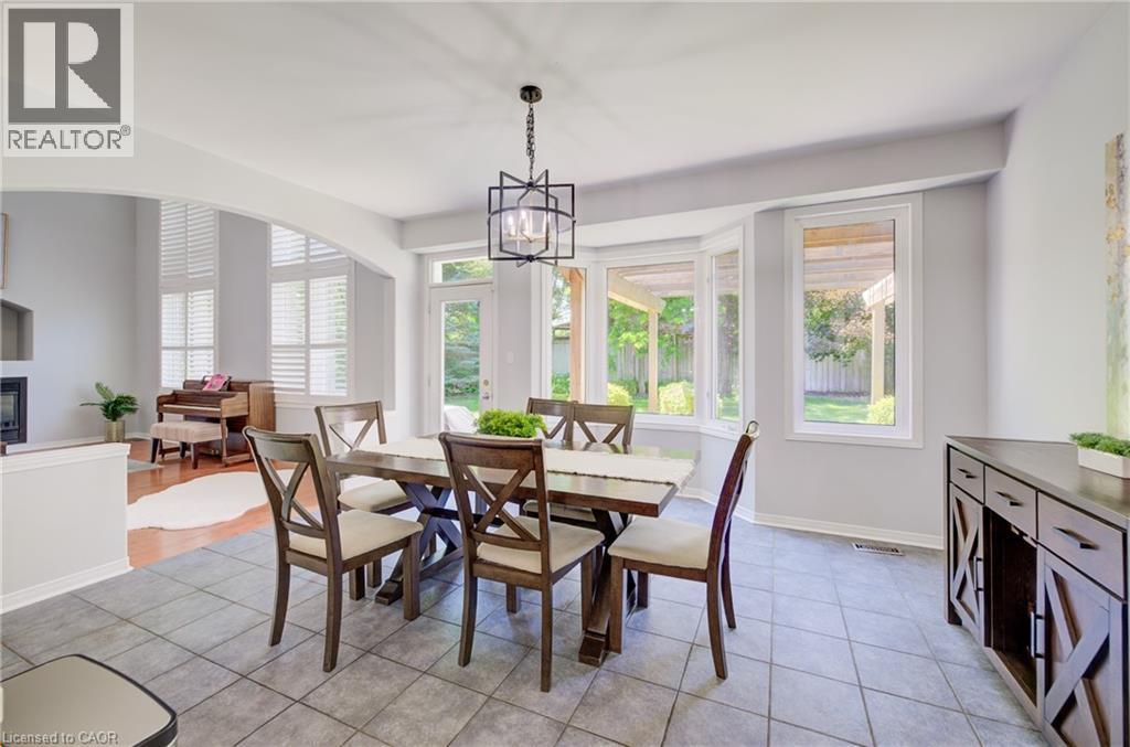 Dining area featuring tile flooring, a geometric chandelier, and an abundance of natural light from multiple windows - 23 Buerkle Court, Kitchener, ON - Indoor Photo Showing Dining Room With Fireplace