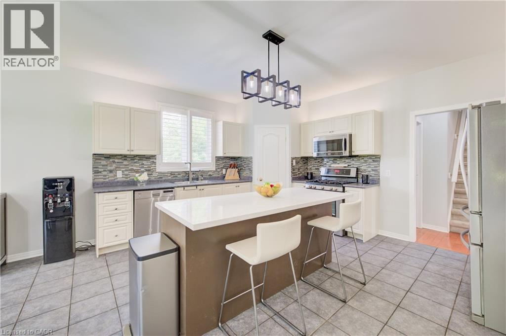 Kitchen featuring a central island with white countertop, recessed lighting, stainless steel appliances, white cabinetry, and tile flooring - 23 Buerkle Court, Kitchener, ON - Indoor