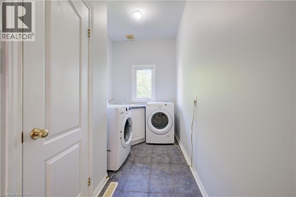 Dedicated laundry area featuring a front-loading washing machine and dryer, tiled flooring, and a single window - 23 Buerkle Court, Kitchener, ON - Indoor Photo Showing Laundry Room