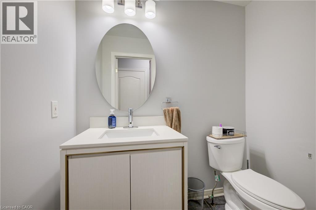 Bathroom featuring a white vanity with integrated sink, chrome faucet, oval mirror, and a three-light fixture - 23 Buerkle Court, Kitchener, ON - Indoor Photo Showing Bathroom