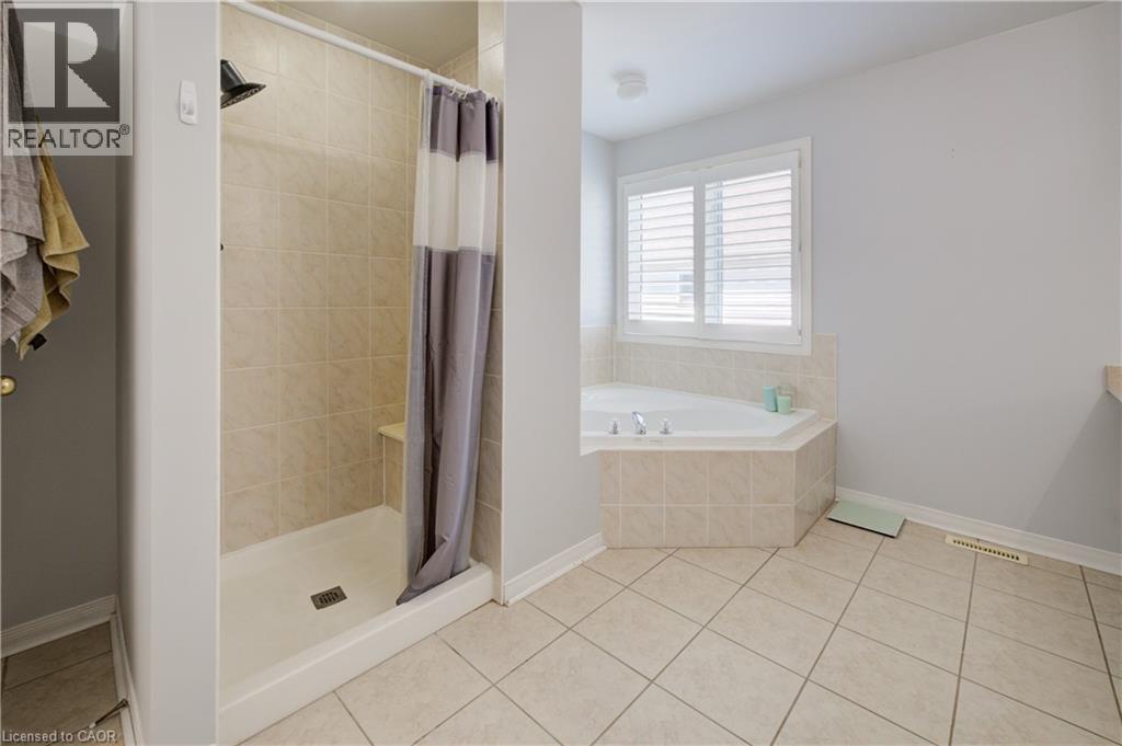Bathroom featuring a tiled stand-up shower with a built-in bench, a corner soaking tub with tiled surround, and a window with white plantation shutters - 23 Buerkle Court, Kitchener, ON - Indoor Photo Showing Bathroom