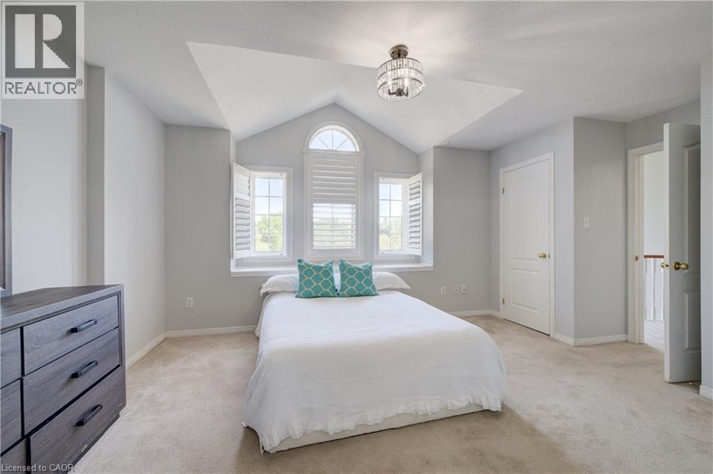 Room featuring vaulted ceiling, arched window, two rectangular windows with plantation shutters, ceiling-mounted light fixture, and carpet flooring - 23 Buerkle Court, Kitchener, ON - Indoor Photo Showing Bedroom