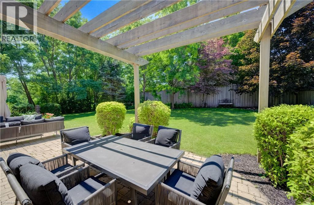 Spacious paver patio featuring a wooden pergola and manicured landscaping - 23 Buerkle Court, Kitchener, ON - Outdoor