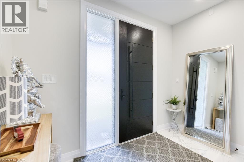 Modern entry featuring a paneled door with long pulls, a textured sidelight, and light-toned flooring - 71 Ian Ormston Drive, Waterloo, ON