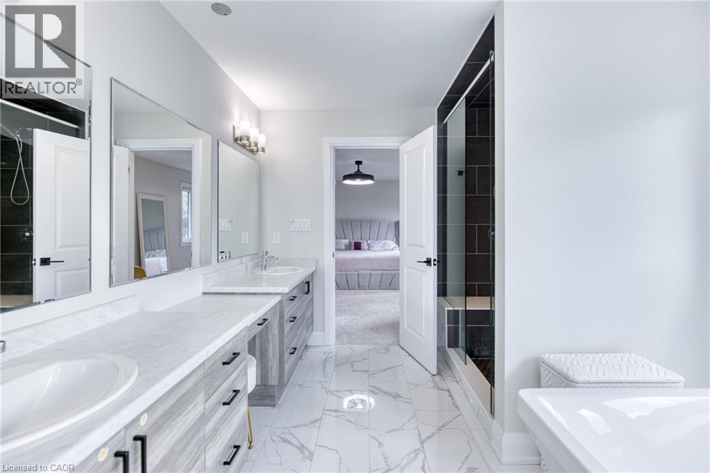 Bathroom featuring a dual vanity with light-toned wood-finish cabinetry and white countertops, a walk-in shower with dark subway tile surround, a built-in shower bench, and white marble-look floor til - 71 Ian Ormston Drive, Waterloo, ON