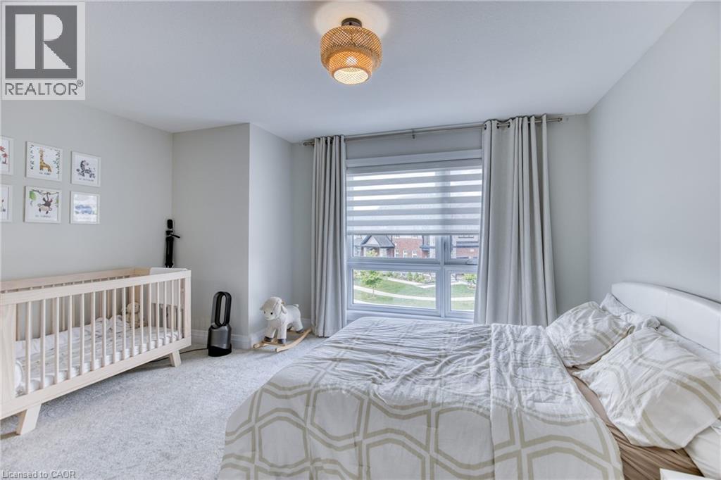 Bedroom with light gray wall paint, light-colored carpet flooring, and a large window featuring blinds and drapes - 71 Ian Ormston Drive, Waterloo, ON