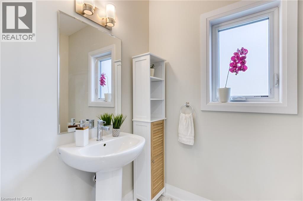 Pedestal sink with chrome faucet, illuminated by a wall-mounted light fixture - 71 Ian Ormston Drive, Waterloo, ON