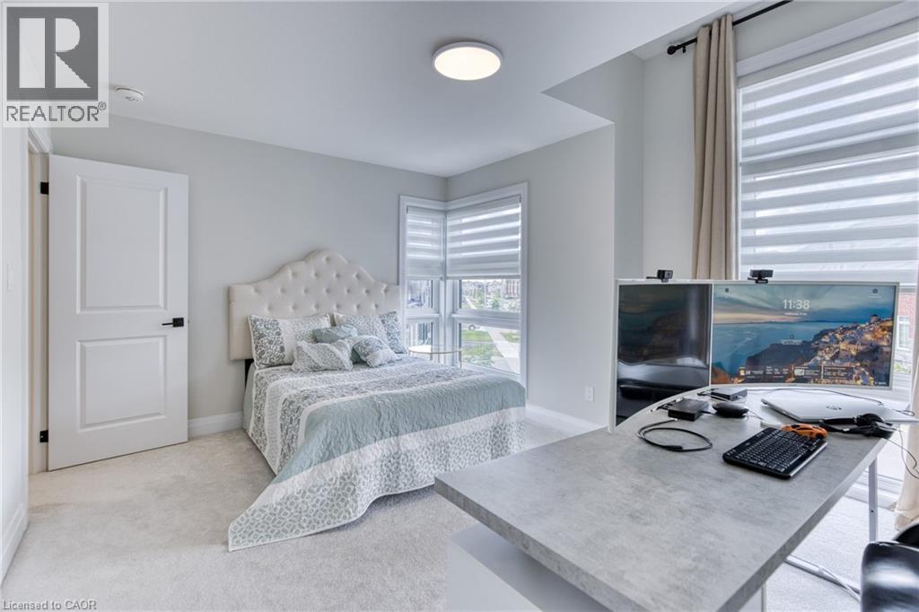 Bedroom featuring wall-to-wall carpeting, white interior door with black hardware, and an upholstered headboard - 71 Ian Ormston Drive, Waterloo, ON