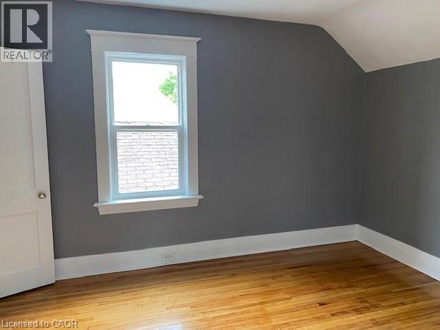 Room featuring wood-finish flooring, a double-hung window with white trim, gray walls, and white baseboards - 1066 Richmond Street, London, ON