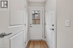 Entryway featuring light wood-finish flooring, white panel doors with brushed nickel hardware, and a rear door with an integrated glass panel providing exterior visibility -