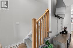 Staircase featuring wood-finish handrails and balusters, carpeted treads, and white risers -