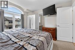 Bedroom featuring an arched window, light-colored walls, white trim, and neutral-toned carpeting -