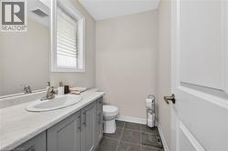 Bathroom vanity featuring a white oval sink with chrome faucet, a light gray countertop, and gray shaker-style cabinetry with brushed nickel hardware -