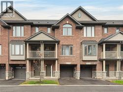 Brick facade townhome featuring an arched window, bay windows, and covered balconies with decorative railings -