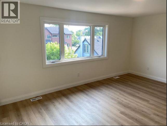 Spacious room featuring wood-finish flooring, white baseboards, and neutral wall paint - 48 Melbourne Street, Hamilton, ON - Indoor Photo Showing Other Room