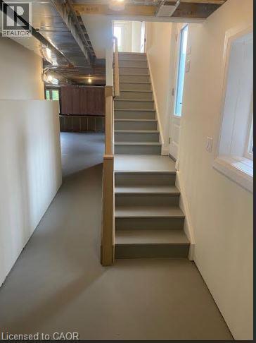 Staircase with painted treads and risers, featuring a wood newel post and a partial glass door - 48 Melbourne Street, Hamilton, ON - Indoor Photo Showing Basement