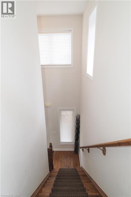 Stairwell featuring a carpeted staircase with wood-finish treads, a wood handrail, and high ceilings - 213 Seabrook Drive, Kitchener, ON