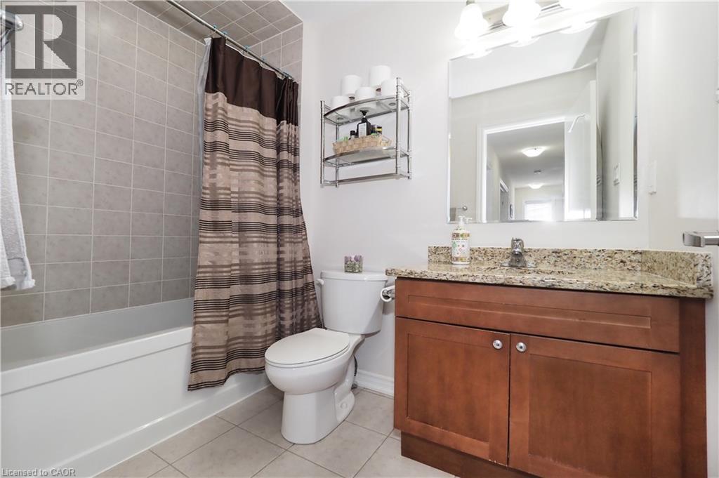 Bathroom featuring a single vanity with wood cabinetry, a light-toned countertop, and a rectangular mirror - 213 Seabrook Drive, Kitchener, ON
