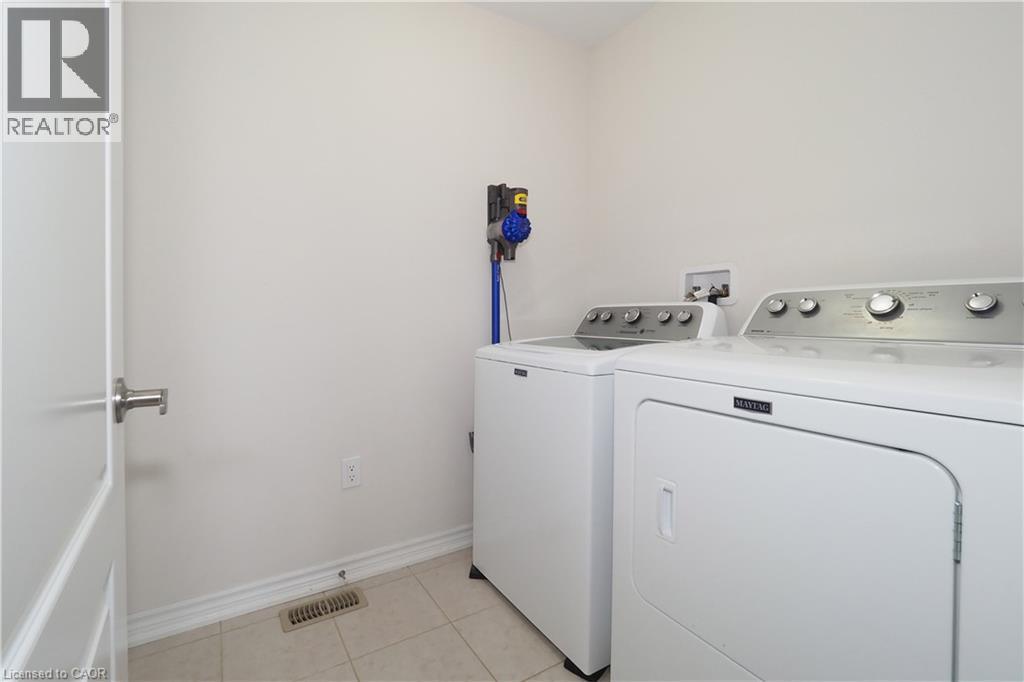 Laundry area featuring neutral wall paint, tile flooring, and a white interior door with brushed nickel hardware - 213 Seabrook Drive, Kitchener, ON