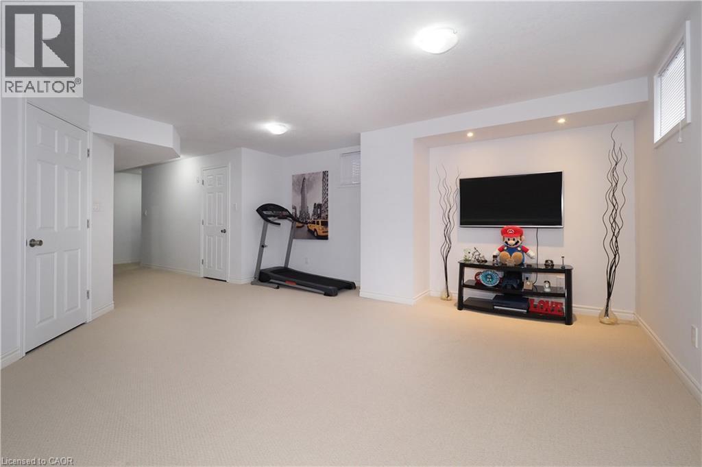 Spacious lower-level room featuring light-colored carpeting, white baseboards, and white painted walls - 213 Seabrook Drive, Kitchener, ON