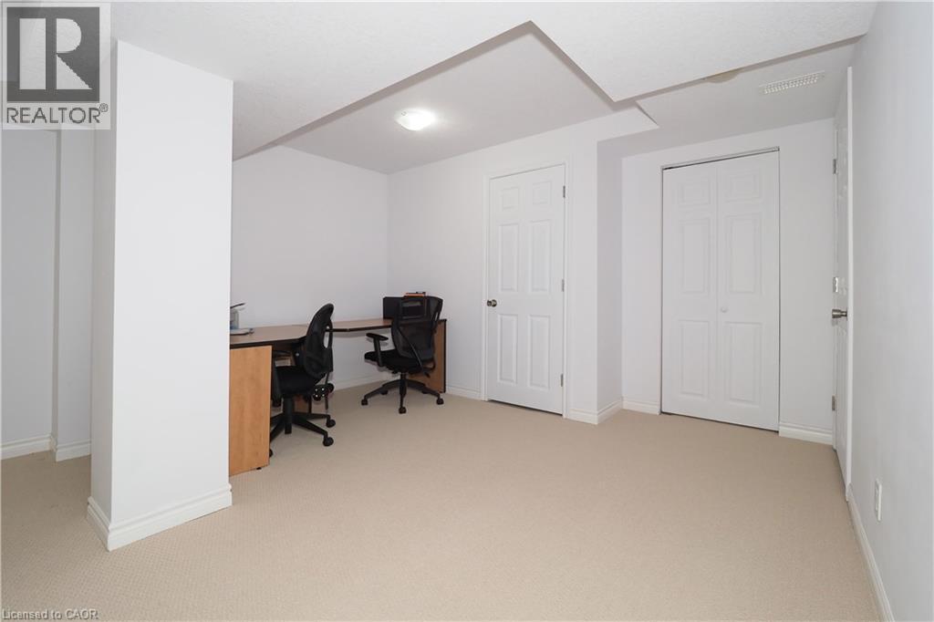 Spacious room featuring neutral carpeting, white walls, and bright overhead lighting - 213 Seabrook Drive, Kitchener, ON