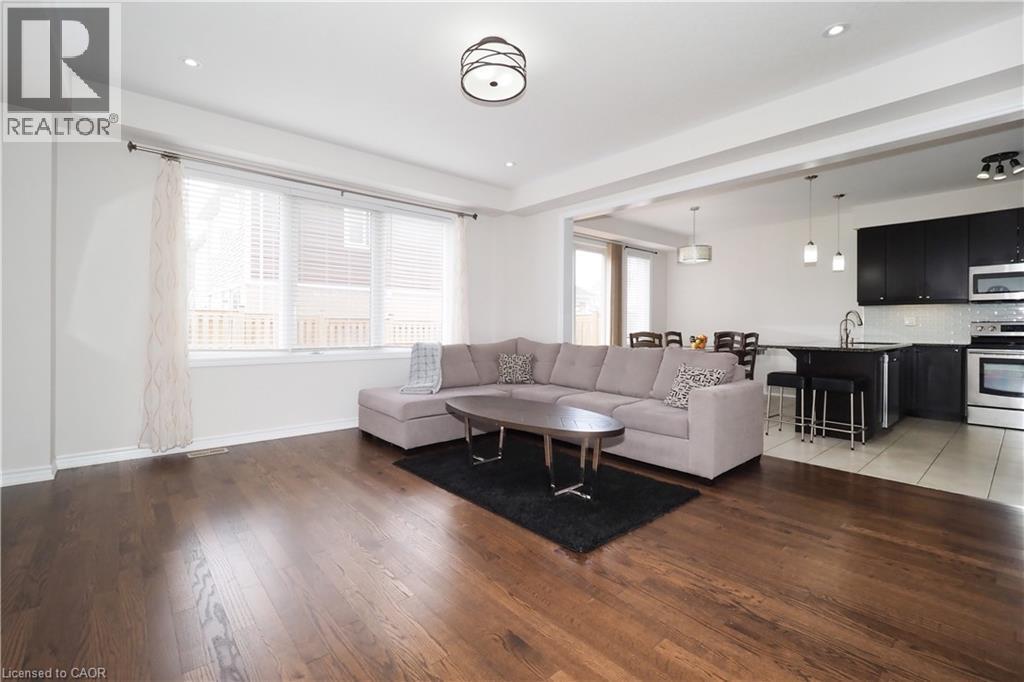 Spacious open-concept living area featuring rich wood-finish flooring, recessed lighting, and a large window - 213 Seabrook Drive, Kitchener, ON