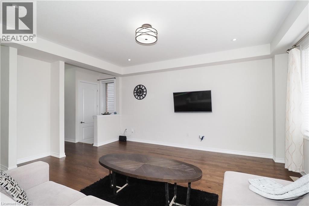 Open living space featuring wood-finish flooring, recessed lighting, a modern ceiling light fixture, and white painted walls - 213 Seabrook Drive, Kitchener, ON