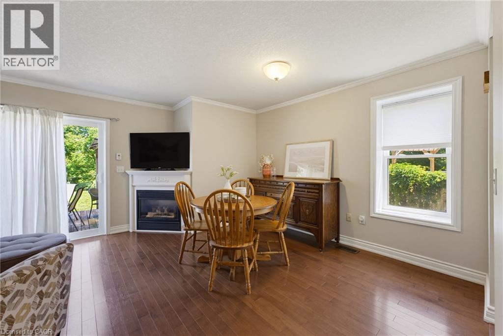 Hardwood-finish flooring extending throughout, complemented by a white mantel fireplace, a large picture window, and a glass sliding door leading to an outdoor area - 520 Mayflower Street, Waterloo, ON - Indoor With Fireplace