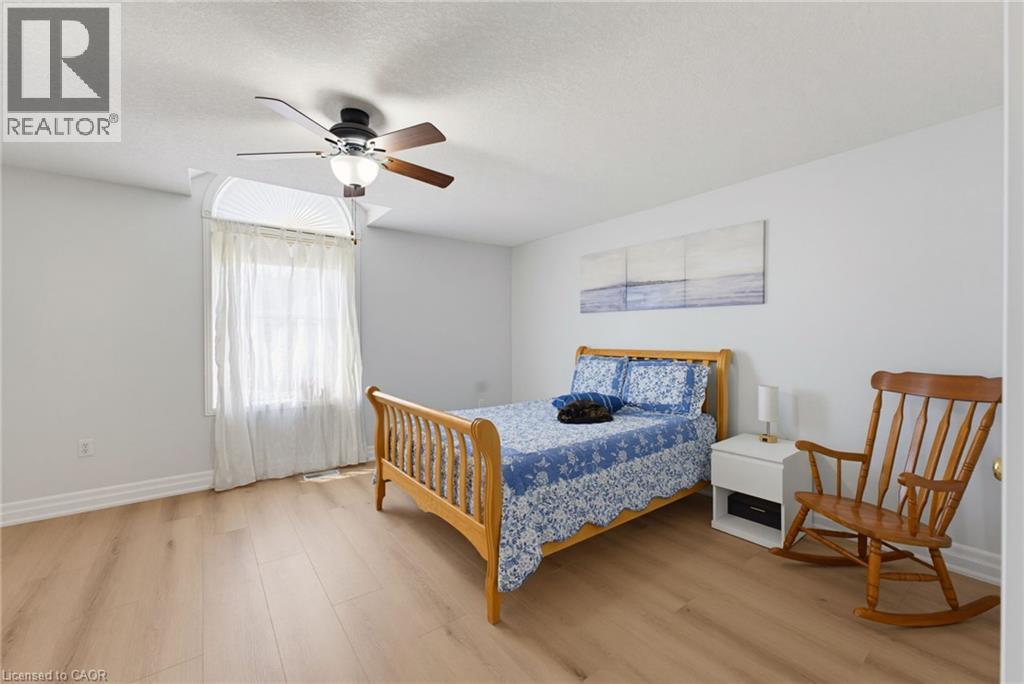 Bright room featuring wood-finish flooring, a ceiling fan with integrated lighting, and a window with an arched top and pleated blinds - 520 Mayflower Street, Waterloo, ON - Indoor Photo Showing Bedroom