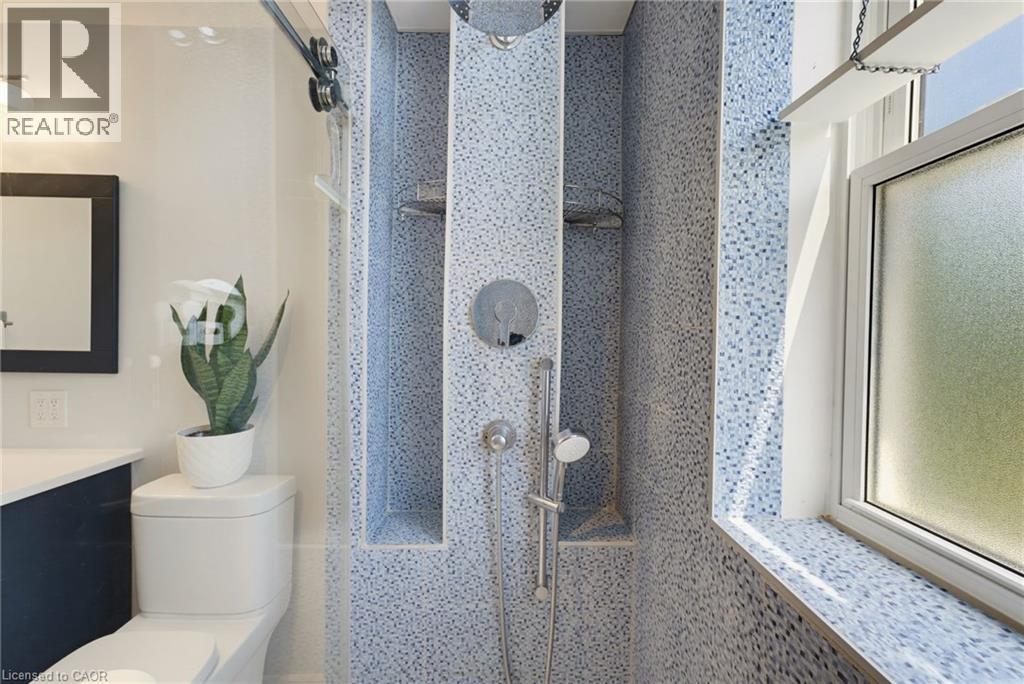 Shower enclosure featuring light blue mosaic tile, a ceiling-mounted rainfall showerhead, and a handheld shower unit - 520 Mayflower Street, Waterloo, ON - Indoor Photo Showing Bathroom