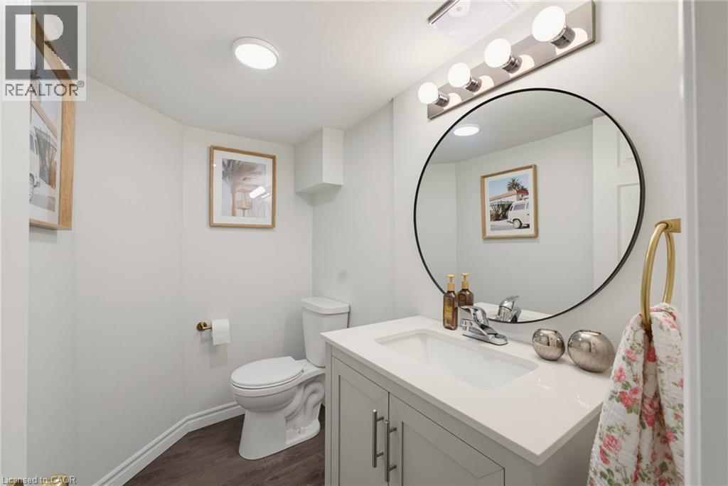 Contemporary bathroom featuring a modern vanity with integrated sink, a large circular mirror, and a five-light vanity fixture - 520 Mayflower Street, Waterloo, ON - Indoor Photo Showing Bathroom