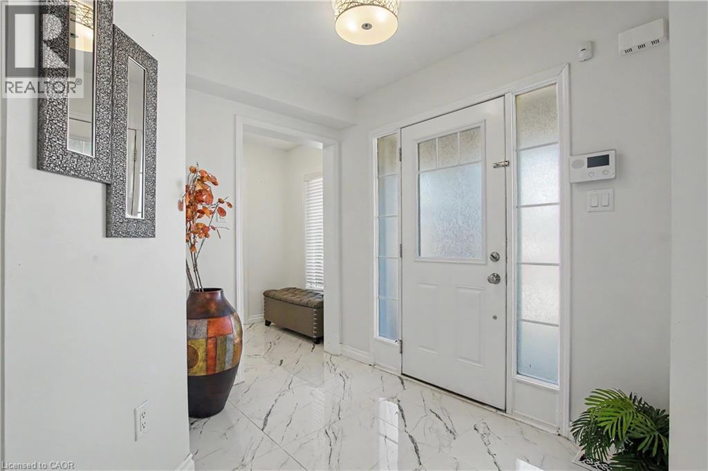 Entryway featuring white tile flooring with dark veining, a white front door with frosted glass inserts, and coordinating frosted sidelight windows - 60 Postmaster Drive, Kitchener, ON - Indoor Photo Showing Other Room