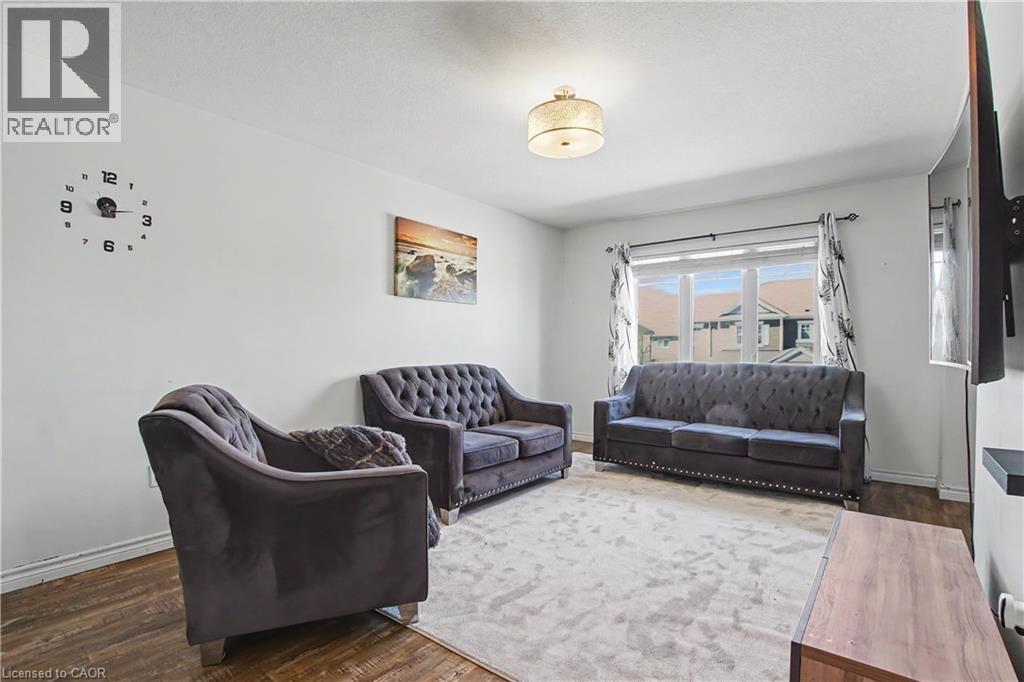 Bright living area featuring wood-finish flooring, white baseboards, and a large window with white trim - 60 Postmaster Drive, Kitchener, ON - Indoor Photo Showing Other Room