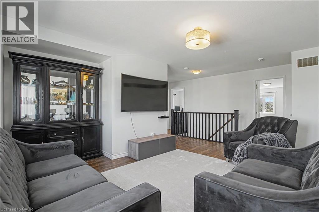 Open concept upper level featuring wood-finish flooring, a carpeted area, and a black wood railing - 60 Postmaster Drive, Kitchener, ON - Indoor Photo Showing Living Room