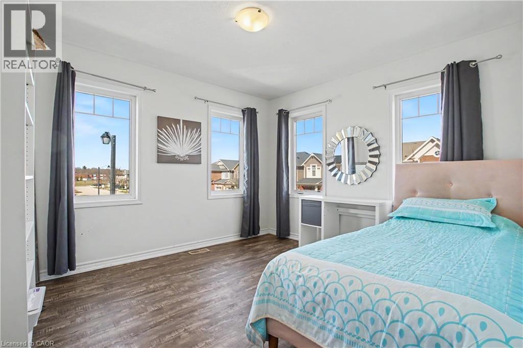 Interior room featuring rich wood-finish flooring, white walls, and multiple windows - 60 Postmaster Drive, Kitchener, ON - Indoor Photo Showing Bedroom