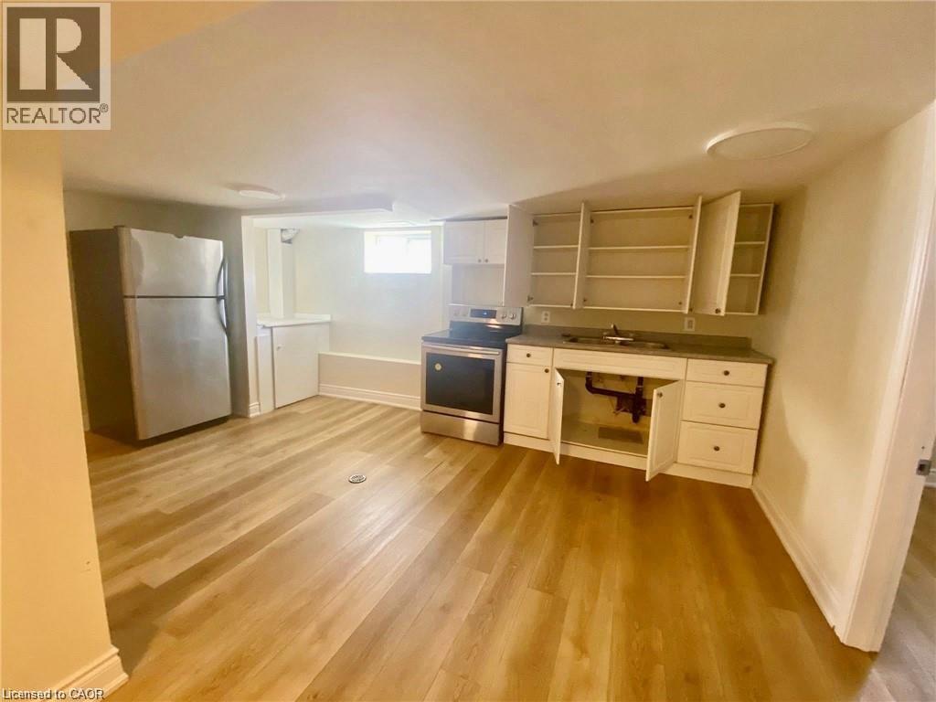 Kitchen area featuring light wood-finish flooring, white cabinetry, and stainless steel appliances - 63 Audrey Street, Hamilton, ON - Indoor Photo Showing Other Room