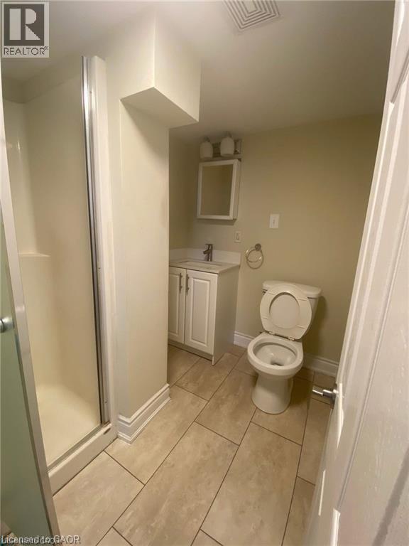 Bathroom featuring a glass-enclosed shower, single vanity with white cabinetry, wall-mounted mirror, and tile flooring - 63 Audrey Street, Hamilton, ON - Indoor Photo Showing Bathroom
