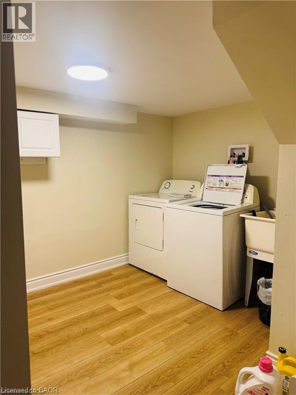 Laundry area featuring wood-finish flooring, a utility sink, and built-in cabinetry - 63 Audrey Street, Hamilton, ON - Indoor Photo Showing Laundry Room